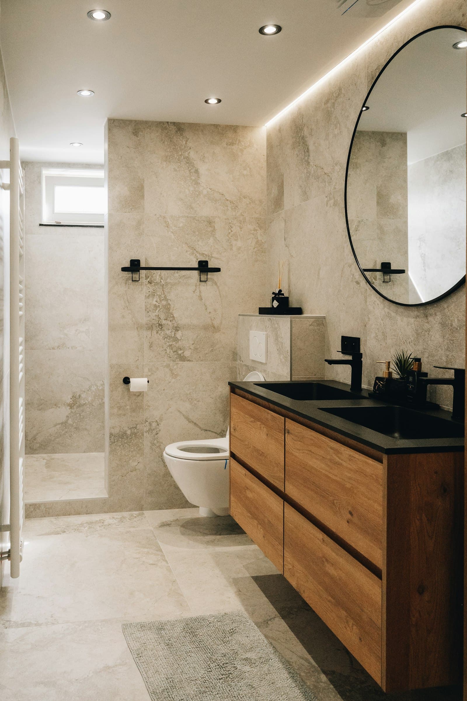 Wood vanity with round mirror and stone tile